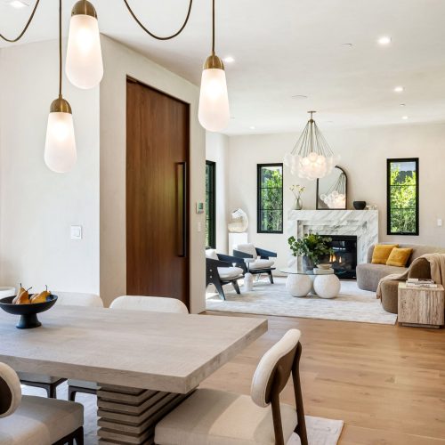 Modern open-plan living and dining area with stylish decor, wooden floors, and large windows offering natural light.